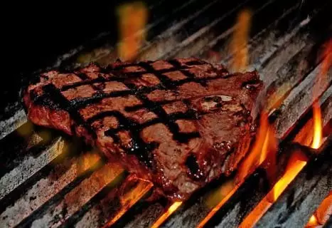 Steak sizzling on a grill.