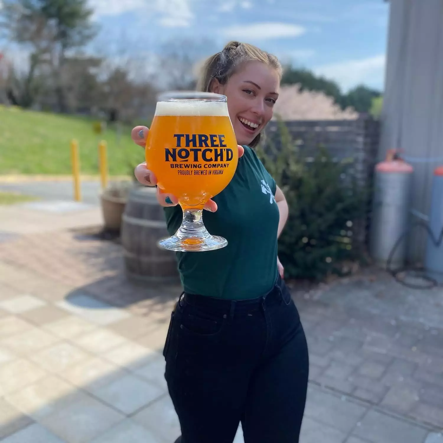 A woman displaying her beer from Three Notch'd Craft Kitchen & Brewery
