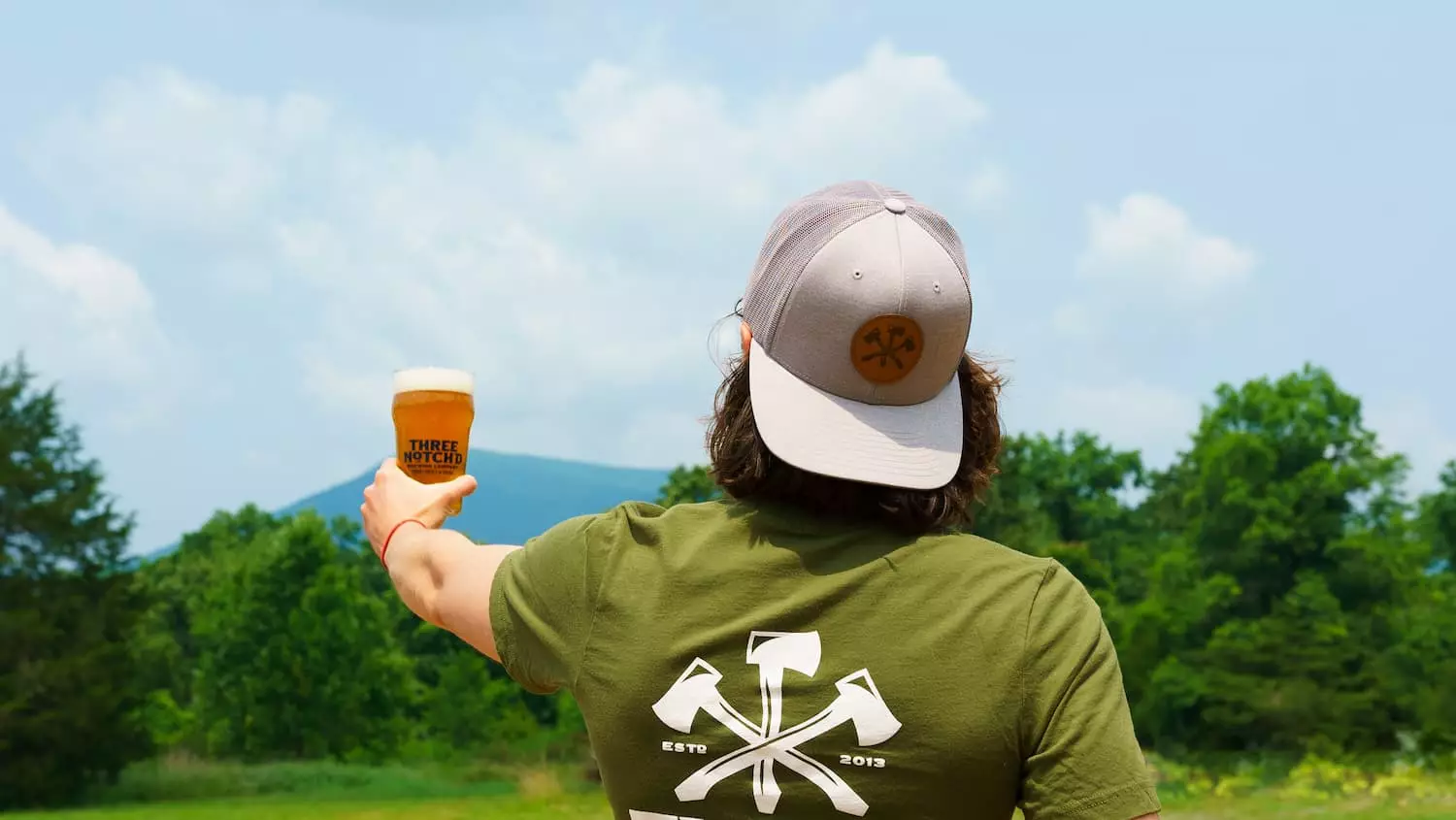 Man displaying his beer from Three Notch'd Brewery, Distillery, and Craft Kitchen